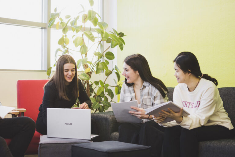 Kolme opiskelijaa istuvat sohvalla ja opiskelevat yhdessä.